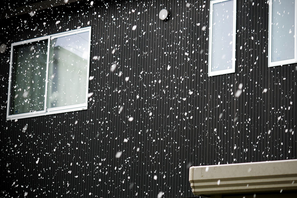 家の外壁と雪が降っている様子