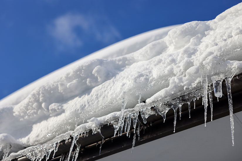 屋根に雪が積もり氷柱が凍っている様子