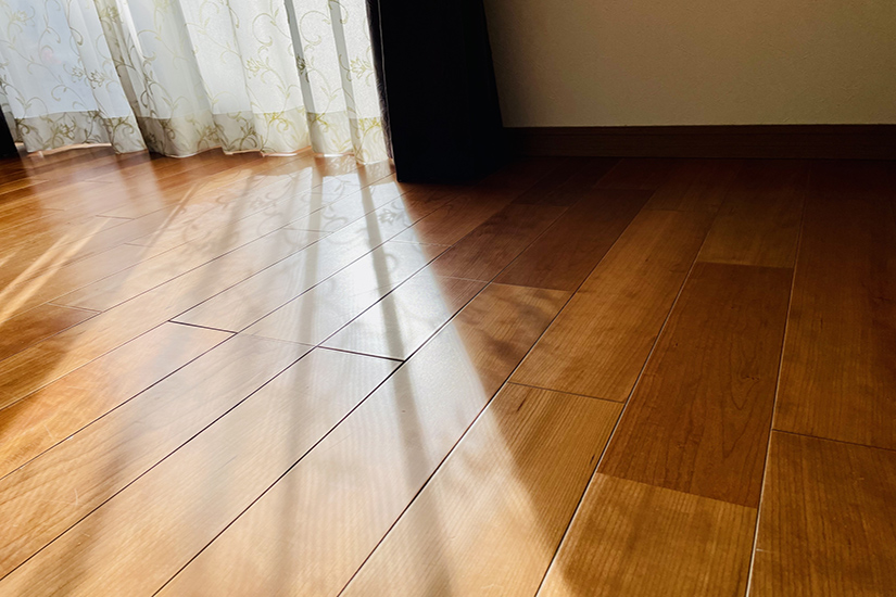 木製フローリングの床に、カーテン越しに日光が差し込む様子の写真