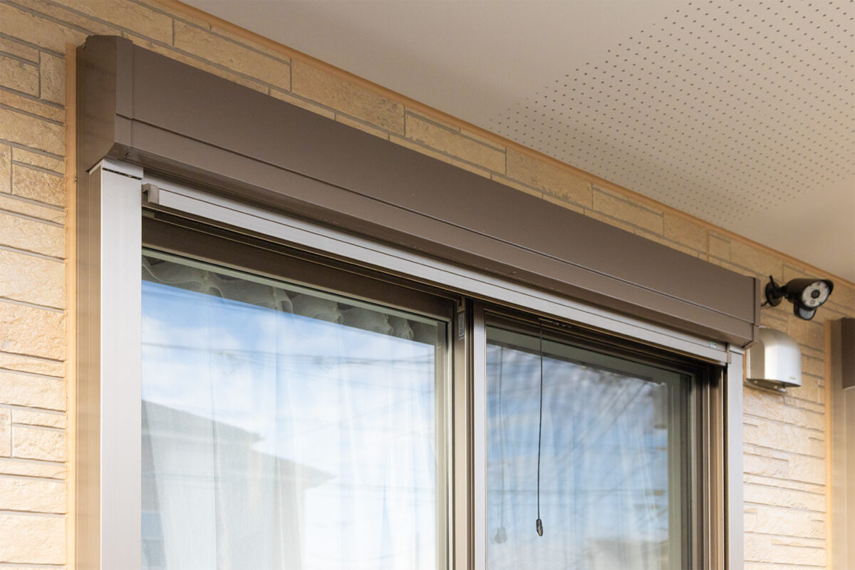 ベージュ系の外壁に取り付けられた掃き出し窓の上部を写した写真