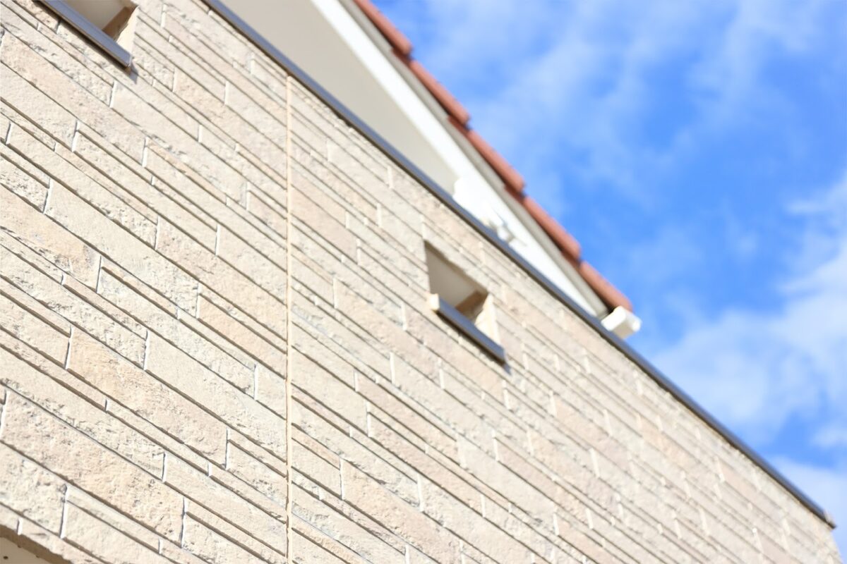 ベージュ系のレンガ調サイディング外壁を見上げたアングルの写真