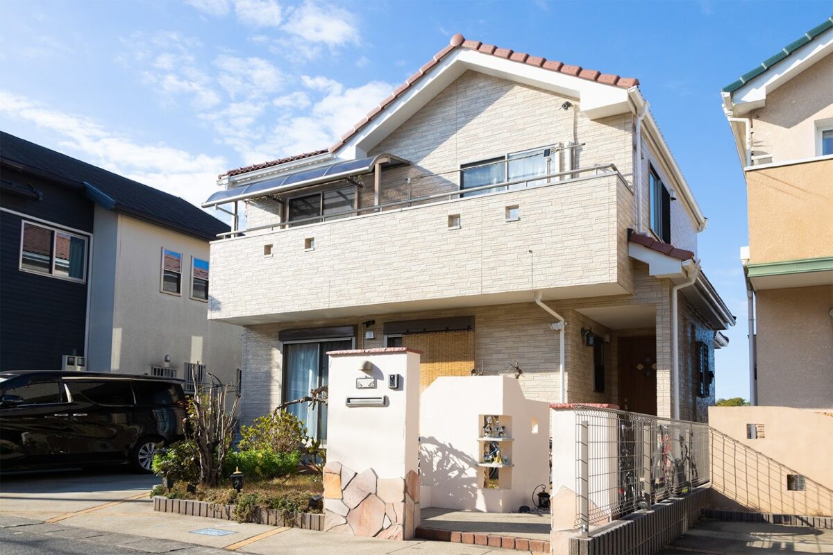 ベージュの外壁と赤茶の屋根が特徴の2階建て住宅の外観。