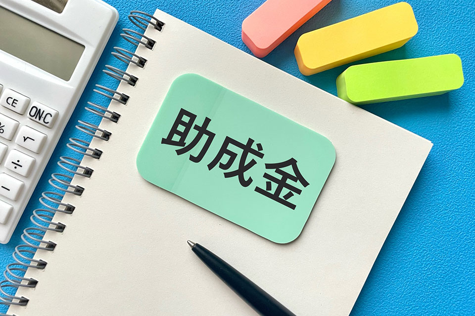 助成金と書かれた付箋がノートに貼られている