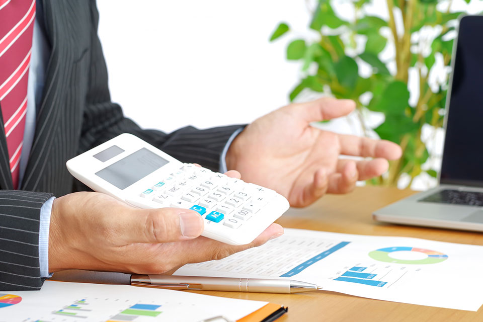 電卓で計算した数字を見せ、説明するスーツの男性