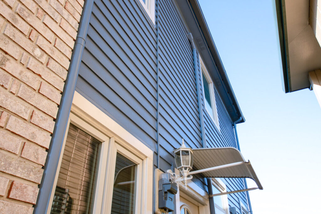 家の裏口側の外壁を写した写真。レンガと青く塗装されたバイカラーの外壁と裏口が写っている。