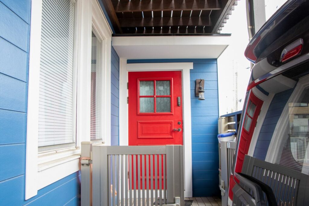 北欧住宅の玄関まわり。白い窓枠と柵の奥に、赤い玄関ドアがある。
