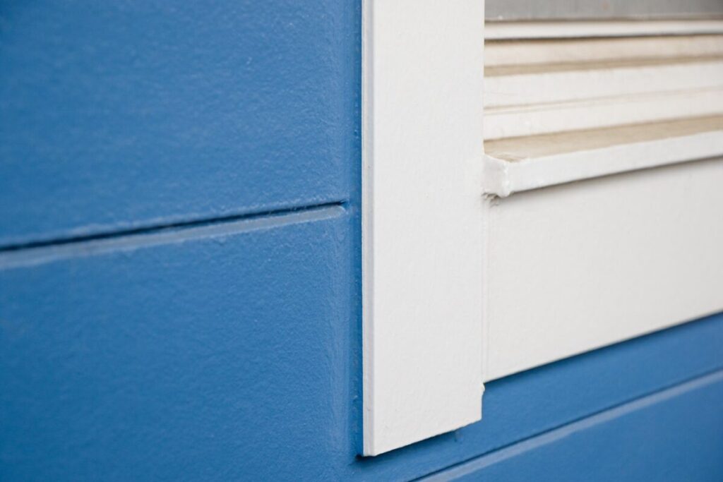 青い外壁と白い窓枠の接合部のクローズアップ。